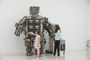 Bild 3: Zwei Kinder vor einer Roboterfigur, die aus mehreren Röhrenbildschirmen und sehr viel technisch anmutenden Knöpfen und Kabeln zusammengesetzt ist.